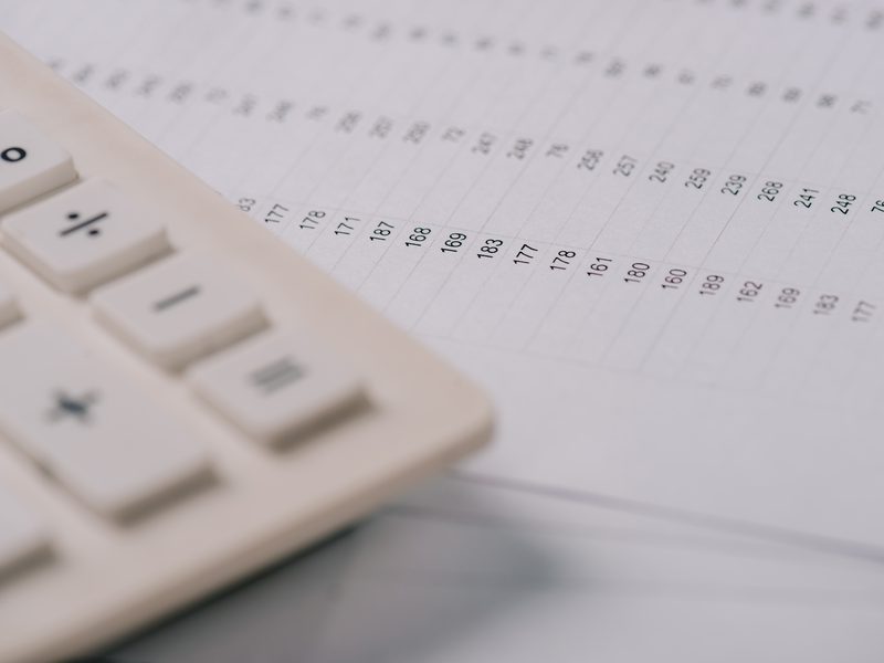 Una calculadora blanca sobre una hoja llena de números
