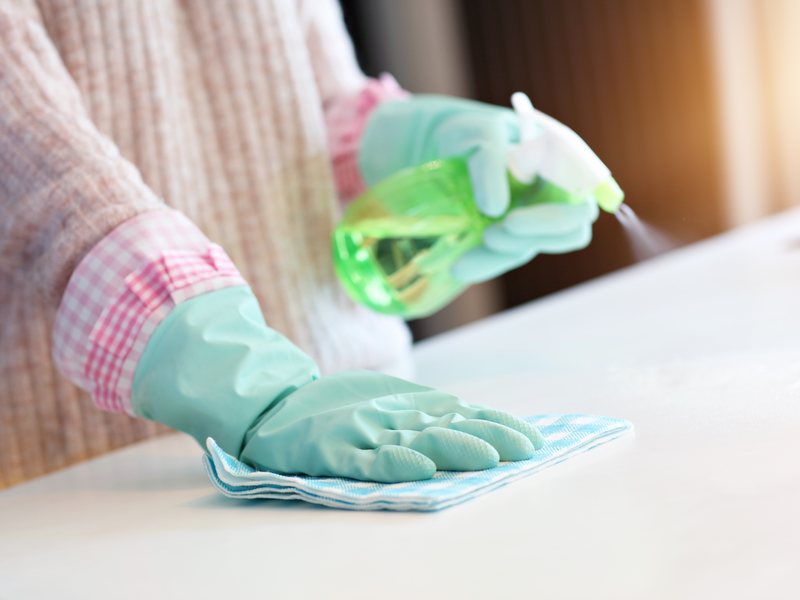 Limpieza a fondo antes de alquilar, alquilar tu piso siendo propietario en Zaragoza Quiero alquilar mi piso en Zaragoza: manos con guantes de goma limpian una encimera blanca con un paño y un pulverizador