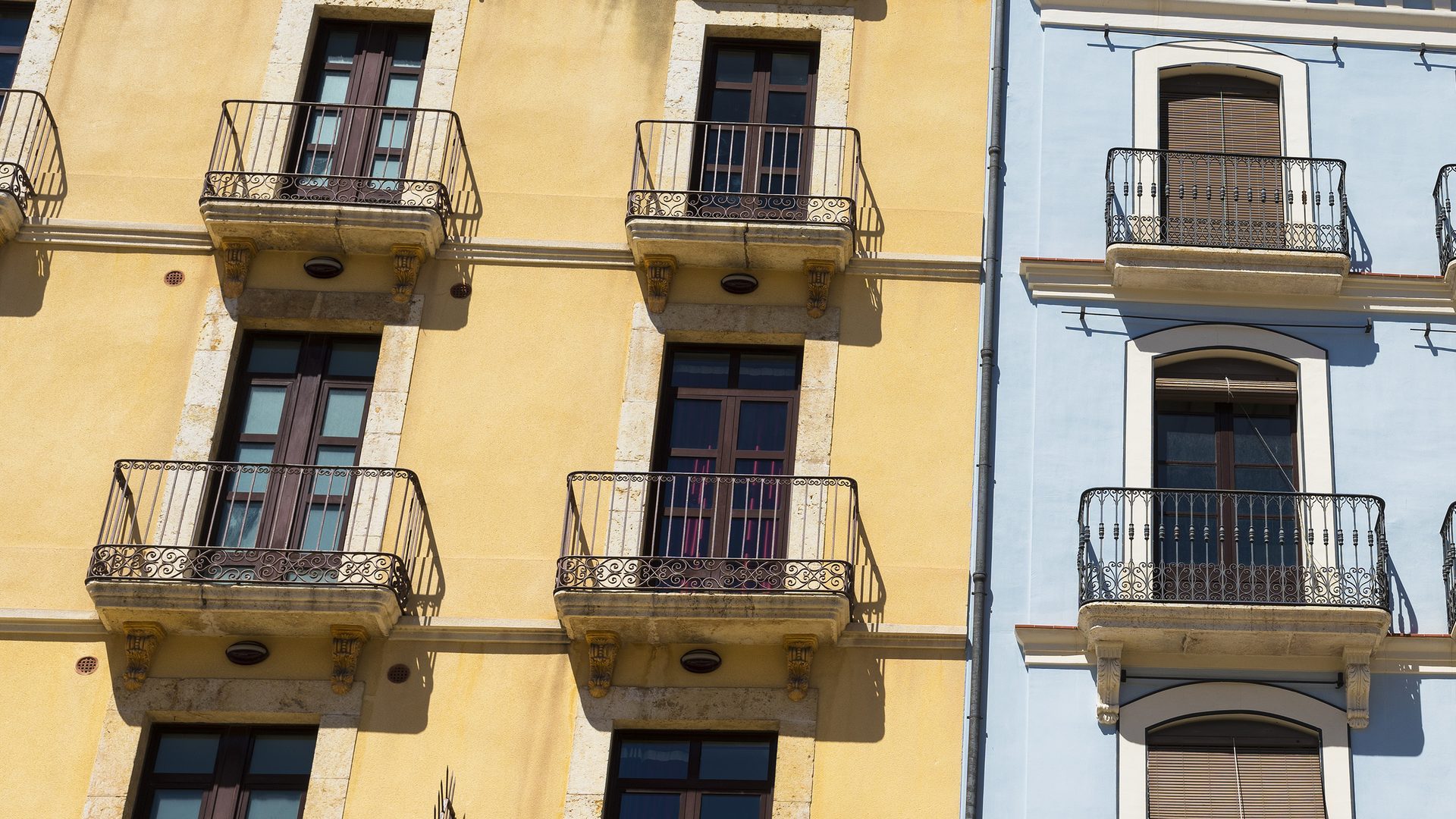 Fachadas de edificios de viviendas antiguos con balcones de hierro