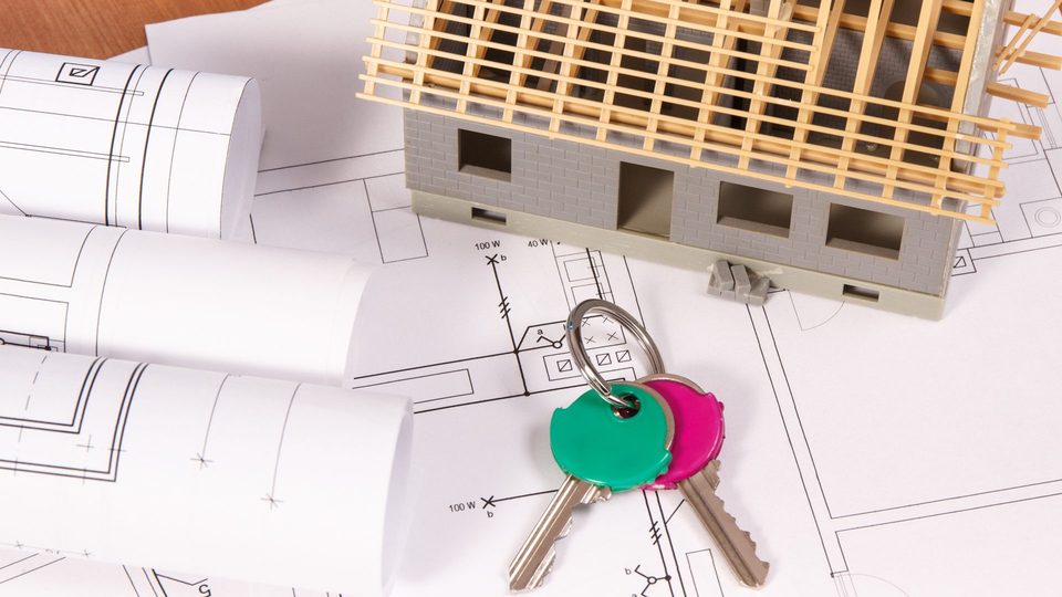 Full property management in Zaragoza: the keys to an apartment on its floor plan, next to a model house